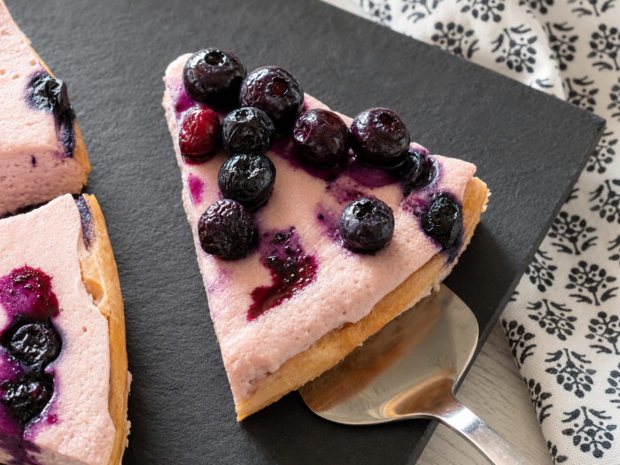 Cremiger Skyrkuchen mit Heidelbeeren als Kuchenstück angeschnitten auf einer Kuchenschaufel