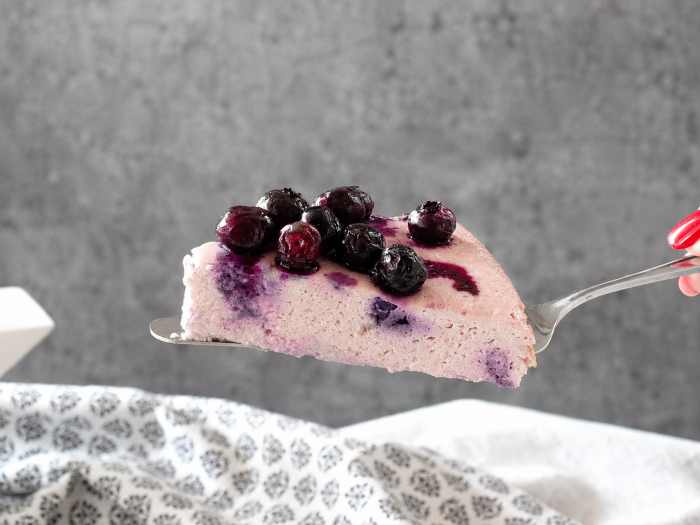 Skyrkuchen mit Heidelbeeren auf einer Kuchenschaufel vor einem grauen Hintergrund