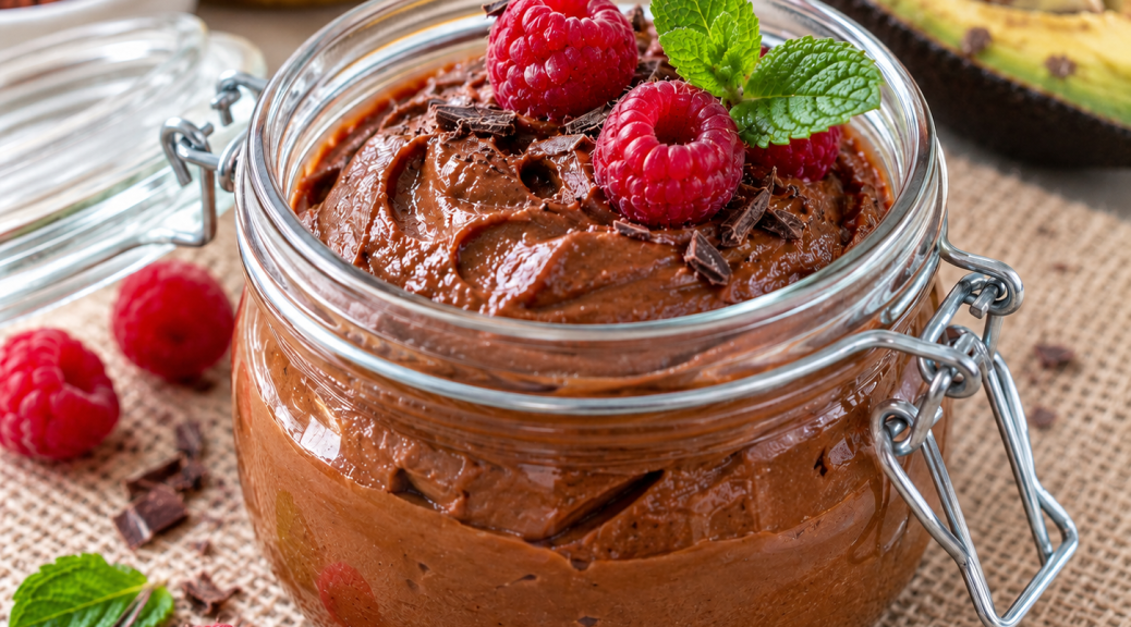 Cremiger veganer Avocado-Schokopudding im Glas mit Himbeeren und Minze, ohne Kochen zubereitet.