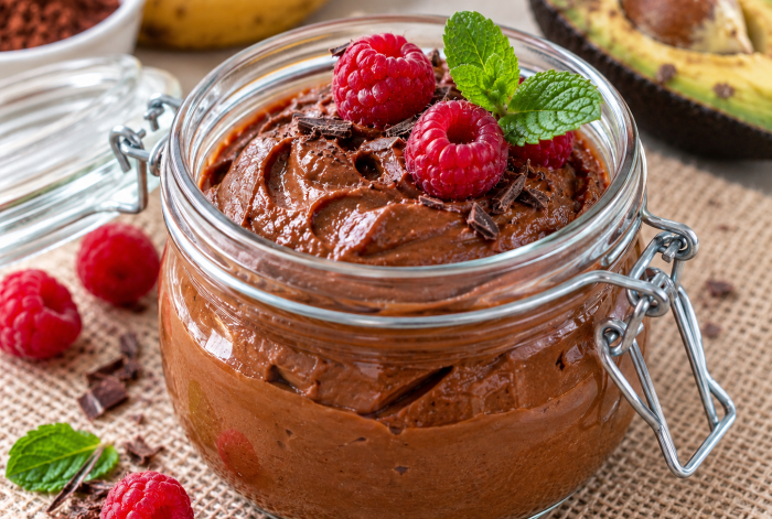 Cremiger veganer Avocado-Schokopudding im Glas mit Himbeeren und Minze, ohne Kochen zubereitet.