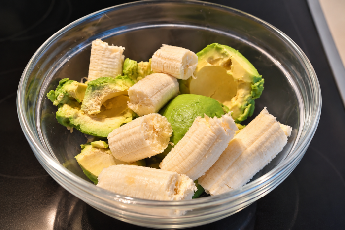 Reife Avocados und Bananen in einer Glasschüssel als Zutaten für veganen Schokopudding.